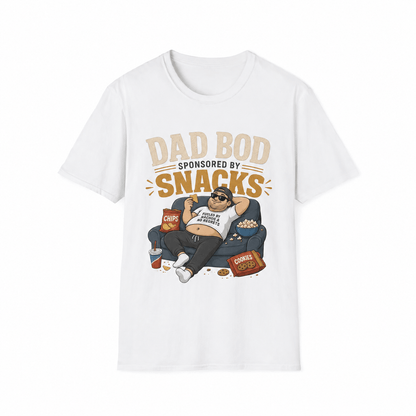 A white short-sleeve crewneck t-shirt featuring a cartoon graphic of a man lounging on a couch surrounded by snacks, with the text 'DAD BOD SPONSORED BY SNACKS' printed above him.